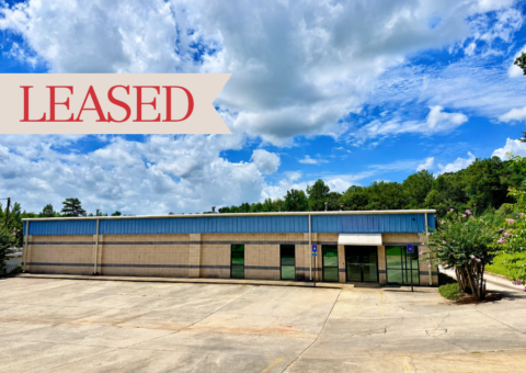 Tan block flex/industrial building with blue metal siding at 255 Collins Industrial Blvd in Athens, GA, shown with a "Leased" banner, glass storefront entry, and a wide concrete parking and loading area.
