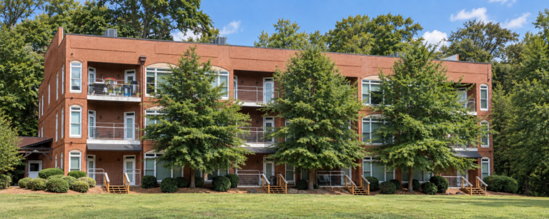 Three-story brick apartment building with balconies and mature trees in Athens, GA